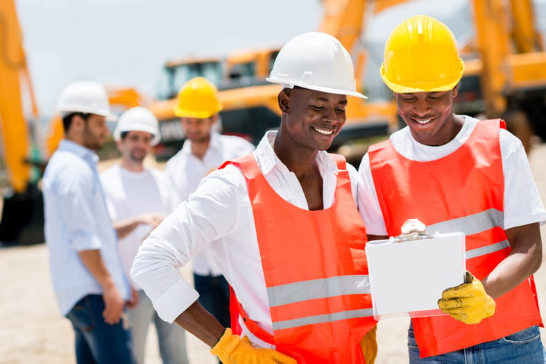 Team of male workers at a building site looking happy